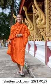 Young Buddhist Monk Walking And Smiling To The Camera. Looking Away