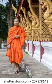 Young Buddhist Monk Walking And Smiling To The Camera. Looking Away