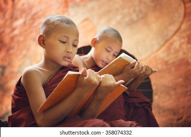 Young Buddhist novice monk reading and study outside monastery, Myanmar.