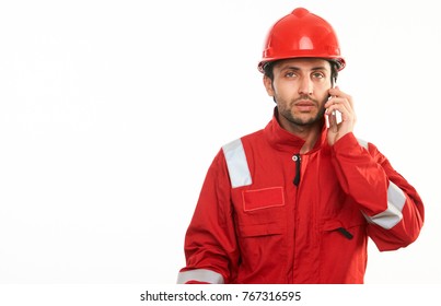 Young Builder Worker In Red Hardhat Helmet And Workwear Uniform Speaks By Mobile Phone Isolated On White Background With Copy Space, Close-up Portrait