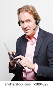 Young Buisness Man In Office With Headset And Tablet Wearing Blue Suit And Pink Shirt. Isolated On White Background.