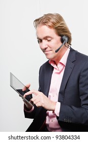 Young Buisness Man In Office With Headset And Tablet Wearing Blue Suit And Pink Shirt. Isolated On White Background.