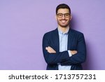 Young buisnessman wearing eyeglasses, jacket and shirt, holding arms crossed, looking at camera with happy confident smile, standing against purple background