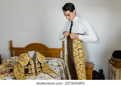 Young bullfighter in bedroom dressing up the lights suit before a bullfight