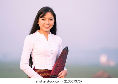 A young Burmese woman holding red umbrella on U-bein bridge, Mandalay, Myanmar. Space for text. - Shutterstock ID 2135073767