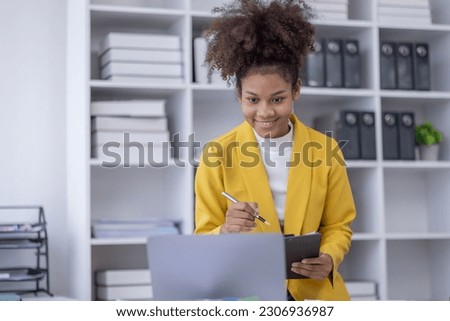 Young business african american woman office worker analyst sitting at desk working on laptop thinking on project plan, analyzing marketing or financial data online, watching elearning webinar.