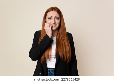 Young business caucasian redhair woman biting fingernails, nervous and very anxious.