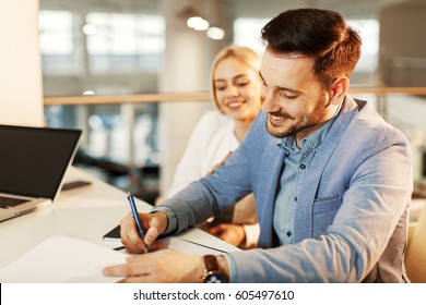 Young business couple signing a contract - Shutterstock ID 605497610