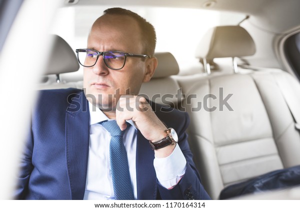 Young business man In the\
back seat in an expensive car with a coded lounge, he goes to a\
meeting...