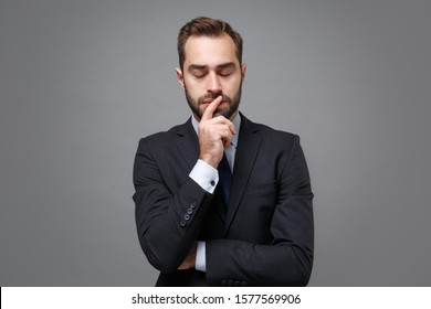 Young business man in classic black suit shirt tie posing isolated on grey background. Achievement career wealth business concept. Mock up copy space. Put hand prop up on chin, keeping eyes closed