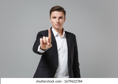 Young Business Man In Classic Black Suit Shirt Isolated On Grey Background. Achievement Career Wealth Business Concept. Touch Something Like Push Click On Button, Pointing At Floating Virtual Screen