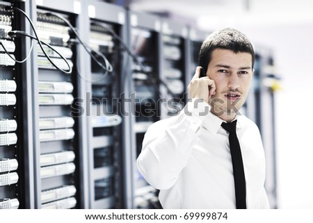 young business man computer science engineer talking by cellphone at network data center server room asking  for help and fast solutions and services