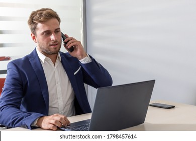 Young Business Man At The Desk In Front Of The Computer And Cell Phone