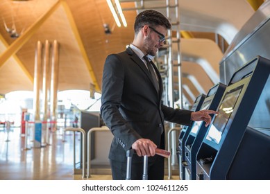 Young business man doing self check in a machine at the airport 