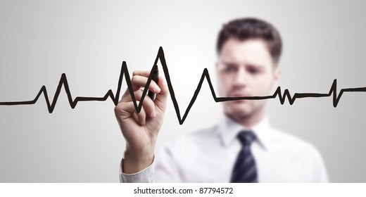 Young Business Man Drawing Chart Heartbeat On A Glass Screen With Black Marker. On A Gray Background