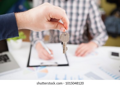 Young business man giving house with keys of customer at agency office