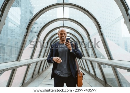 Young business man going to get his flight in the morning passing by a glass corridor in the airport.Representation of a successful sales person reaching the top of the career.