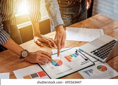 Young Business Man Hand Holding Pen And Partner Pointing Graph Chart For  Analyze The Company's Sales Plan In The Office.