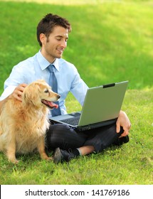 Young Business Man And His Dog Working Outdoors With Laptop On The Grass