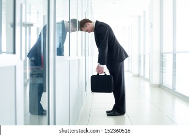 young business man leaned against glass wall in crisis moment 
