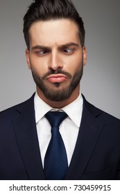 young business man making a stupid face on grey background