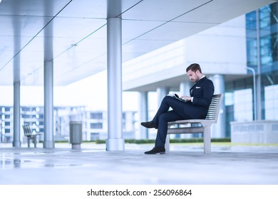 Young Business Man At Office Building Reading Newspaper.
