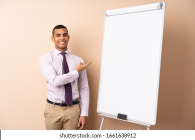 Young Business Man Over Isolated Background Giving A Presentation On White Board And Pointing To The Side