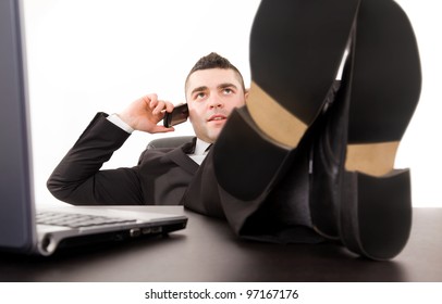 Young Business Man Relaxing At Office Desk And Talking On Mobile Phone, Isolated On White