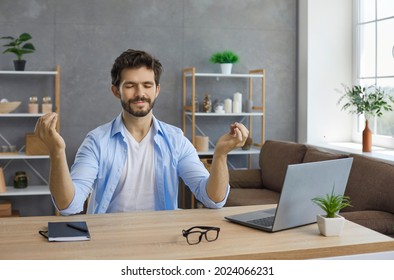 Young Business Man Sitting At Working Desk With Laptop In Home Office, Meditating With Eyes Closed, Trying To Calm Down, Think Of Good Things, Focus On Positive Feelings And Emotions And Reduce Stress