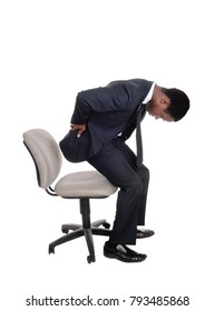 A Young Business Man In A Suit Getting Up From His Office Chair Holding 
His Back For Back Pain, Isolated For White Background
