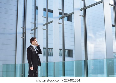 Young Business Man Talking By Phone In Office High Tech  Bright Interior