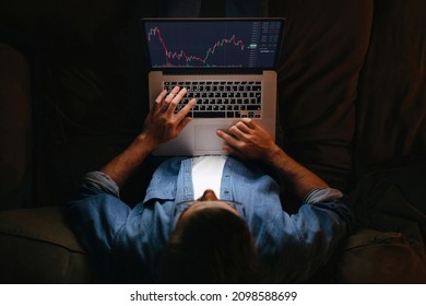 Young business man trader analyst looking at laptop monitor on sofa, investor broker analyzing indexes, financial chart trading online investment data on cryptocurrency stock market graph. Top view - Shutterstock ID 2098588699