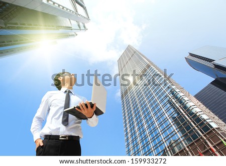 Young business man using laptop and look to blue sky and cloud with cityscape, hong kong, asia, business and cloud computing concept