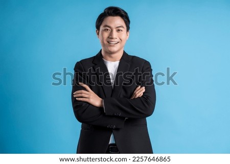 Young business man wearing a vest posing on a blue background