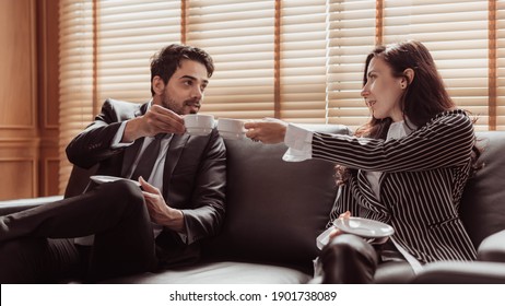 Young business man and woman working together and drinking coffee in office. Two business people drinking coffee and discuss about project. Business and working concept.