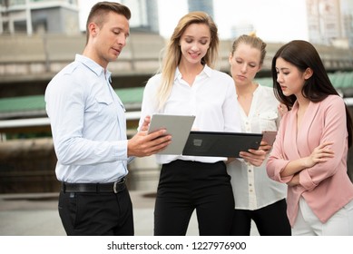 Young Business Man And Women Teamwork Talking While Standing Outdoor On City Background,looking At Ipad With Exciting Emotion As  A  Good News On Tablet,goal,business Success Concept,selective Focus.