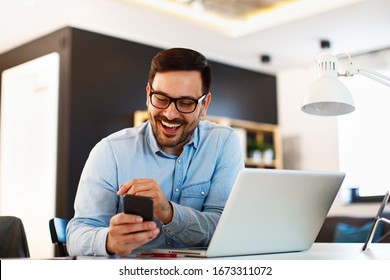 Young business man working at home with laptop and uses a smartphone