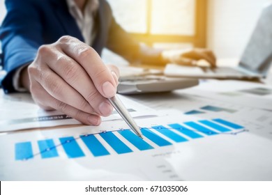 Young Business Man Working At Office With Laptop Computer ,calculator And Graph Data Documents   For  Plans To Improve Quality Next Month On His Desk.