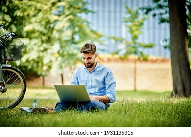 Young business man working on laptop in park - Powered by Shutterstock