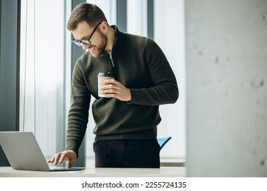 Young business man working on computer aqnd drinking coffee at the office - Shutterstock ID 2255724135