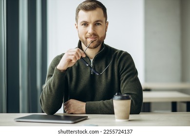 Young business man working on computer aqnd drinking coffee at the office - Shutterstock ID 2255724137
