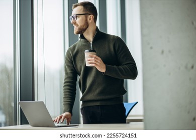 Young business man working on computer aqnd drinking coffee at the office - Shutterstock ID 2255724151