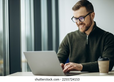 Young business man working on computer aqnd drinking coffee at the office - Shutterstock ID 2255724153