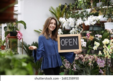 Young business owner holding OPEN sign in flower shop - Powered by Shutterstock