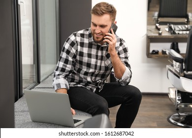 Young Business Owner Talking On Phone In His Barber Shop