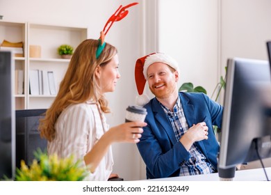 Young Business People Celebrating Christmas At The Office, Wearing Santa Hat And Antlers And Having Conversation While Taking A Coffee Break