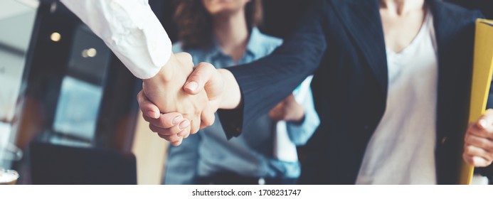 Young business people shaking hands in the office. Finishing successful meeting. Three persons. Wide screen panoramic - Shutterstock ID 1708231747