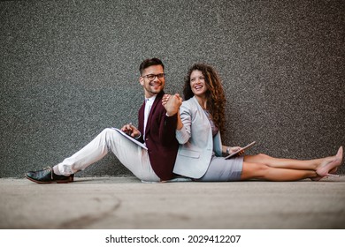 Young Business People Sitting Down In Front Of A Modern Office Building 