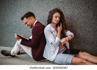 Young Business People Sitting Down In Front Of A Modern Office Building 