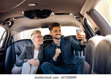 Young business people taking selfie in limo